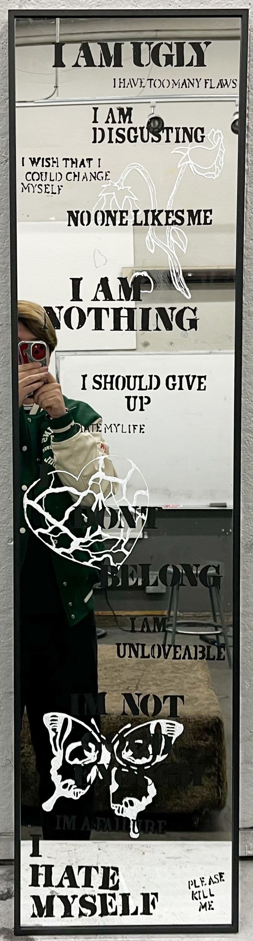 Mirror with various words painted on to it, buttefly drawings on it with negative mantra.